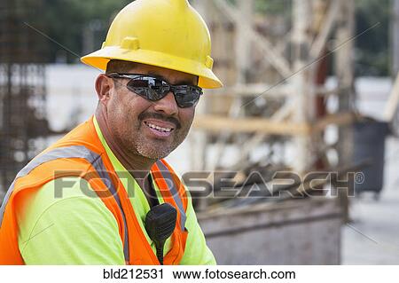 Stock Image - Hispanic worker smiling at construction site. Fotosearch