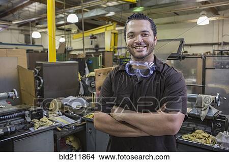 Picture - Hispanic worker smiling in repair shop. Fotosearch