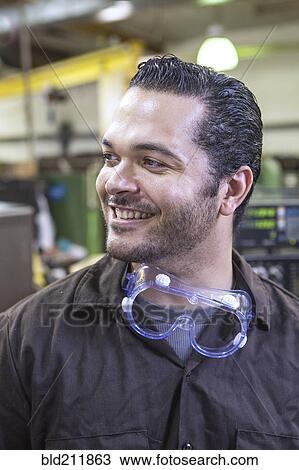 Stock Image - Hispanic worker smiling in warehouse. Fotosearch