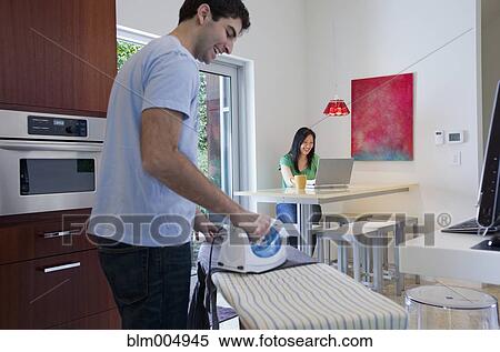 Husband ironing while wife uses laptop View Large Photo Image Stock Photography - Husband ironing while wife uses laptop. Fotosearch