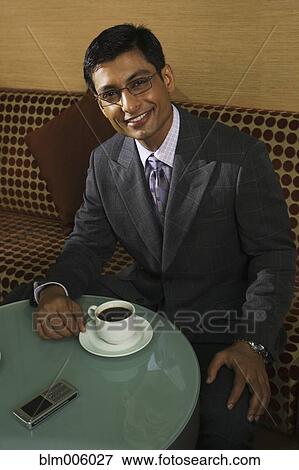 Stock Photo - Indian businessman drinking coffee in cafe. Fotosearch