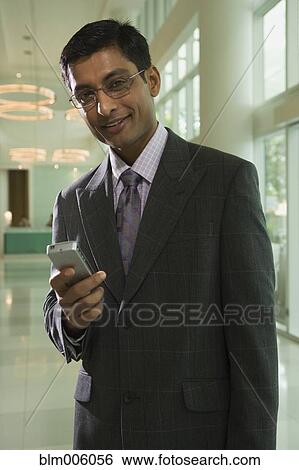 Indian businessman holding cell phone View Large Photo Image Stock Photograph - Indian businessman holding cell phone. Fotosearch
