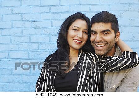 Stock Photo - Indian couple hugging along blue brick wall. Fotosearch