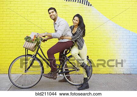 Picture - Indian couple riding bicycle on city street. Fotosearch