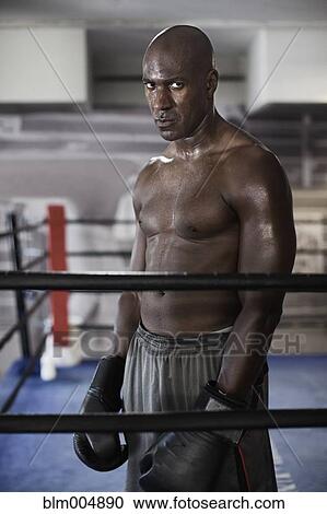 Stock Image - Intense African boxer standing in boxing ring. Fotosearch
