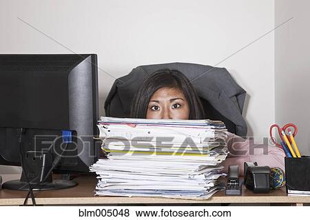 Stock Photo - Japanese businesswoman hiding behind stack of papers. Fotosearch