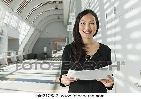 Japanese businesswoman holding papers in office View Large Photo Image Stock Image - Japanese businesswoman holding papers in office. Fotosearch