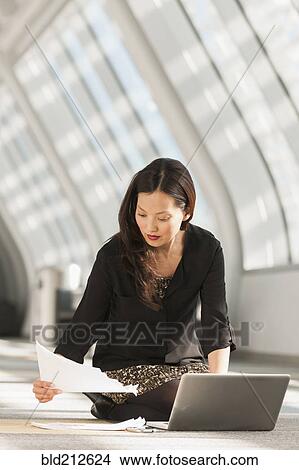 Picture - Japanese businesswoman using laptop on lobby floor. Fotosearch