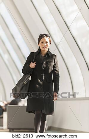 Stock Image - Japanese businesswoman walking in lobby. Fotosearch