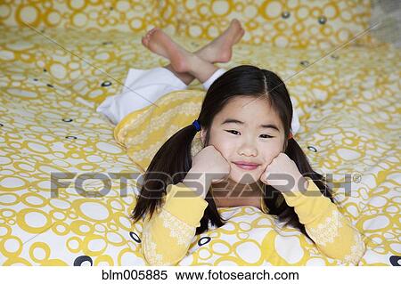 Stock Photography - Japanese girl laying on bed. Fotosearch