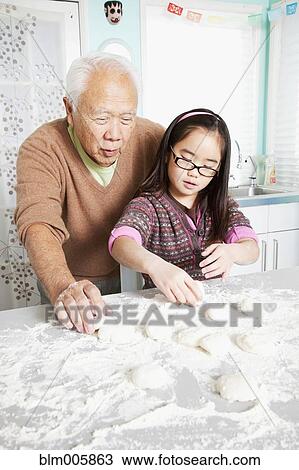 Stock Image - Japanese grandfather and granddaughter baking. Fotosearch