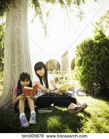 Stock Photo - Japanese mother and daughter reading in park. Fotosearch