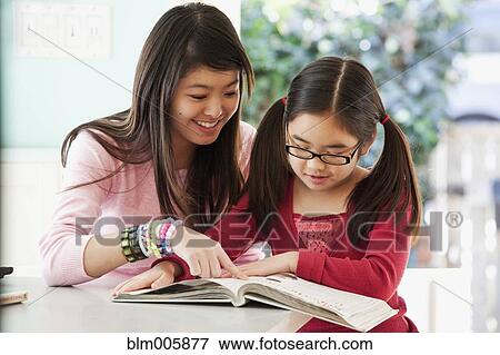 Stock Photo - Japanese teenager helping sister with homework. Fotosearch