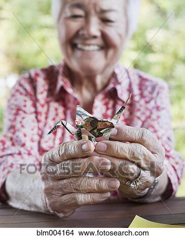 Picture - Japanese woman holding origami bird. Fotosearch