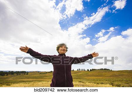 Stock Image - Japanese woman standing in rural landscape, Yellowstone, Wyoming, United States. Fotosearch