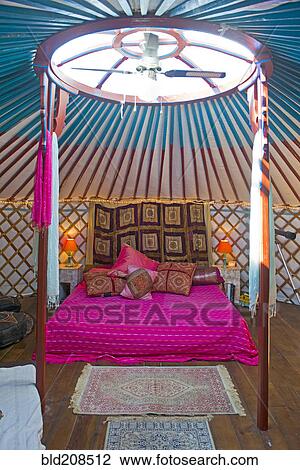 Stock Image - King size bed in a Mongolian yurt with skylight and fan. Fotosearch