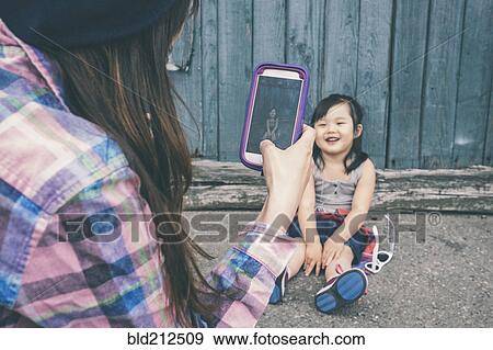 Korean mother taking pictures of daughter on city street View Large Photo Image Stock Photo - Korean mother taking pictures of daughter on city street. Fotosearch