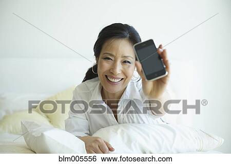 Stock Photograph - Korean woman holding out cell phone. Fotosearch