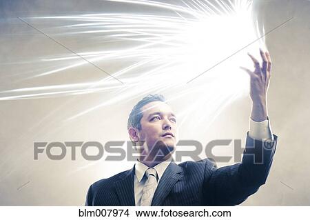 Picture - Light radiating from Japanese businessman's hands. Fotosearch
