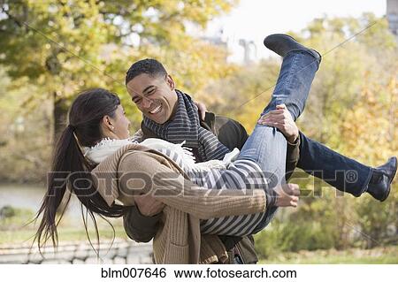 Man carrying girlfriend in park View Large Photo Image Stock Photograph - Man carrying girlfriend in park. Fotosearch