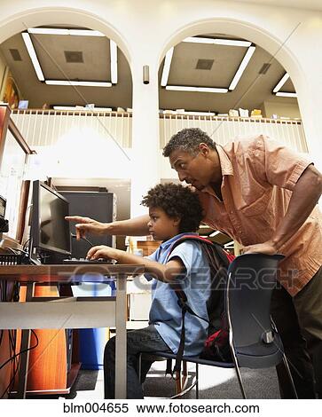 Stock Photography - Man helping mixed race boy use computer. Fotosearch
