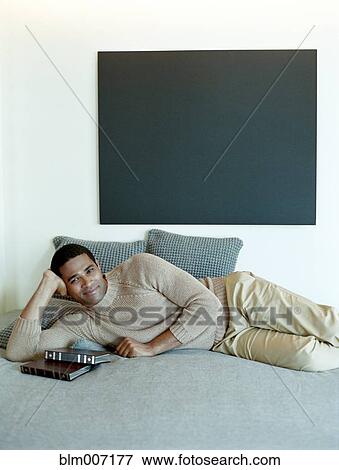 Stock Photo - Man laying on bed with books. Fotosearch