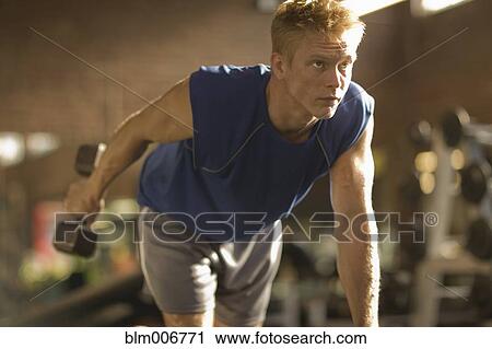 Man lifting weights in health club View Large Photo Image Stock Image - Man lifting weights in health club. Fotosearch