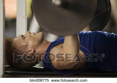Stock Photography - Man lifting weights in health club. Fotosearch