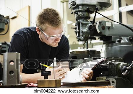 Man looking at notes in machine shop View Large Photo Image Stock Image - Man looking at notes in machine shop. Fotosearch