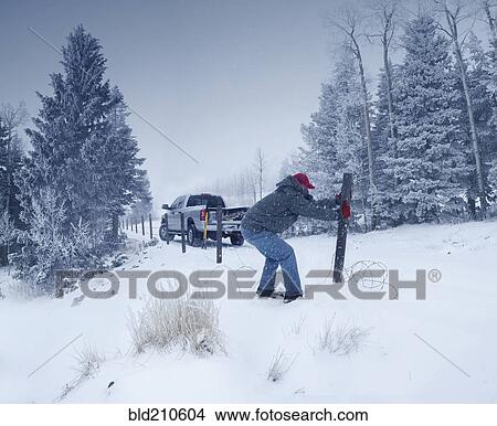 Man repairing wooden post in snowy ground View Large Photo Image Picture - Man repairing wooden post in snowy ground. Fotosearch