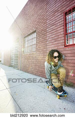 Stock Image - Man riding skateboard on city street. Fotosearch