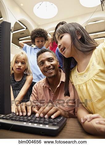 Man showing group of children how to use computer View Large Photo Image Stock Photograph - Man showing group of children how to use computer. Fotosearch