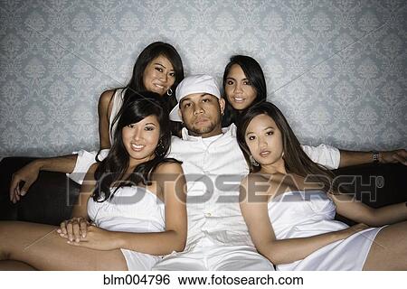 Stock Photograph - Man sitting on sofa with four women. Fotosearch