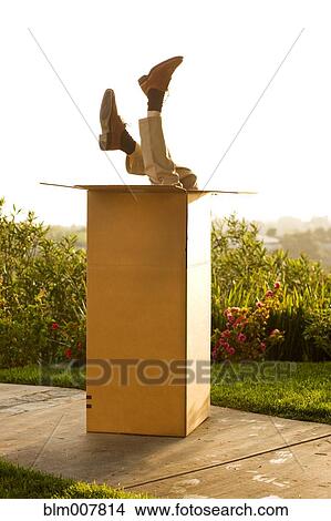 Picture - Man upside-down in cardboard box. Fotosearch