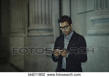 Stock Image - Man using cell phone on city street. Fotosearch