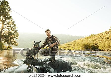 Man with dog fishing in river View Large Photo Image Picture - Man with dog fishing in river. Fotosearch