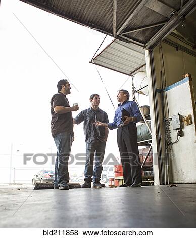 Stock Photo - Manager and workers talking at warehouse loading dock. Fotosearch
