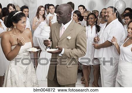 Stock Image - Married couple eating cake at wedding reception. Fotosearch