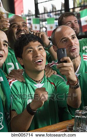 Picture - Men in sports bar using camera phone. Fotosearch