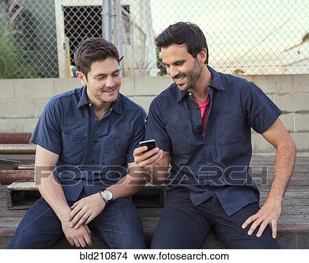 Picture - Men using cell phone outdoors. Fotosearch