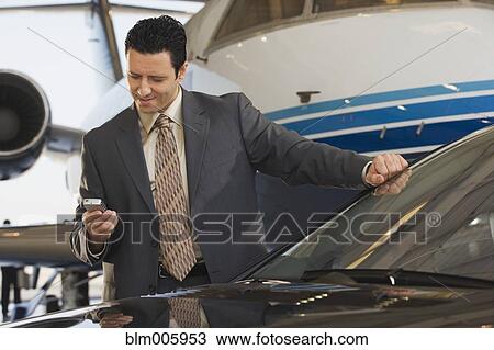 Stock Image - Middle Eastern businessman text messaging on cell phone. Fotosearch