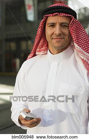 Middle Eastern man in traditional clothing with cell phone View Large Photo Image Stock Photo - Middle Eastern man in traditional clothing with cell phone. Fotosearch