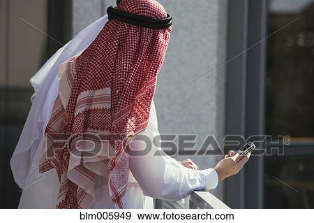 Stock Photo - Middle Eastern man in traditional clothing with cell phone. Fotosearch