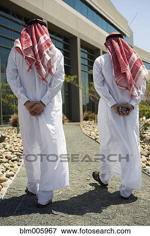 Middle Eastern men in traditional clothing walking on path View Large Photo Image Stock Photo - Middle Eastern men in traditional clothing walking on path. Fotosearch