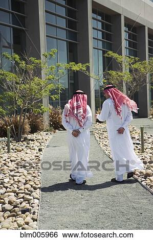 Middle Eastern men in traditional clothing walking on path View Large Photo Image Stock Photograph - Middle Eastern men in traditional clothing walking on path. Fotosearch