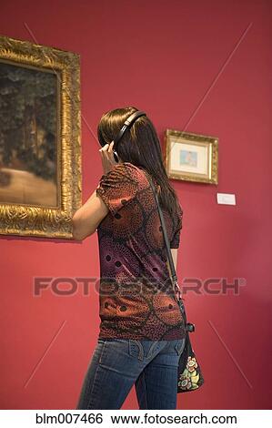 Stock Photograph - Middle Eastern woman admiring painting in museum. Fotosearch