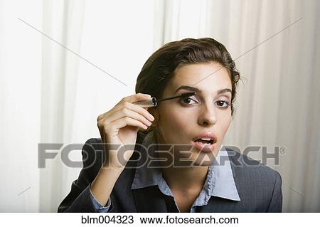 Stock Image - Middle Eastern woman applying mascara. Fotosearch