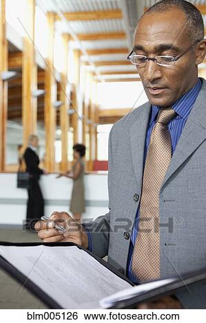 Stock Photograph - Mixed businessman looking at paperwork. Fotosearch
