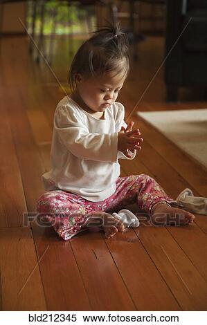 Stock Photography - Mixed race baby with Down syndrome playing on floor. Fotosearch