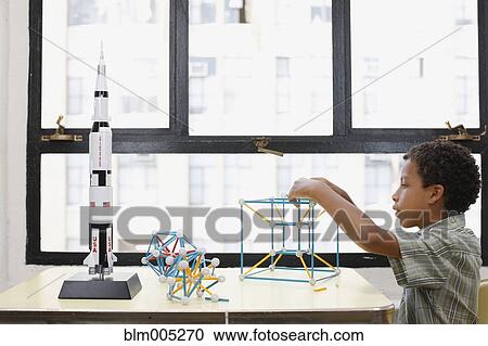 Stock Image - Mixed race boy building geometric shape. Fotosearch